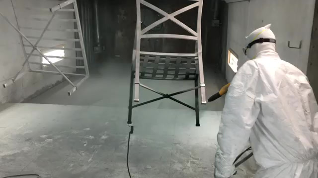A technician applying powder coating inside the Quality Powder Coating facility